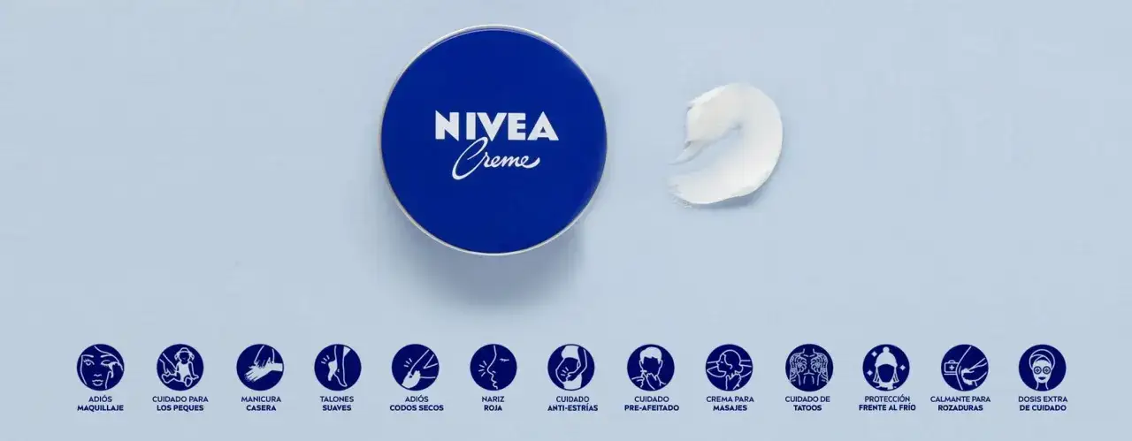 Lata azul de Nivea Creme, con una gota de crema. Muestra usos variados, desde adiós maquillaje hasta cuidado de tatuajes. ¡La crema Nivea lata azul es mala para la piel seca!
