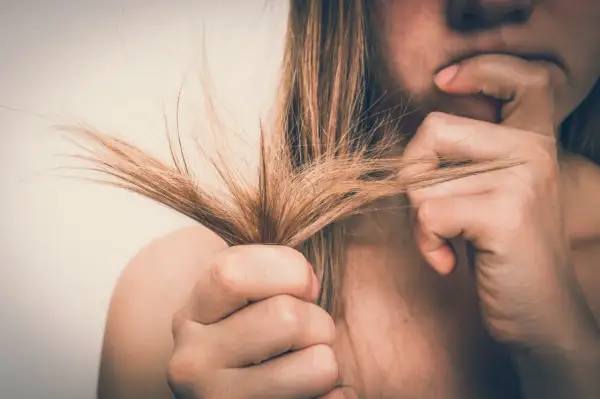 Mujer preocupada por su cabello seco y dañado. El alcohol bencílico puede ser un ingrediente útil para mejorar la salud del cabello.