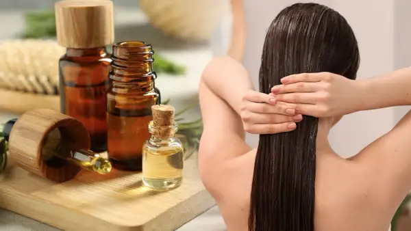 Aceite de romero para el pelo, aplicado en cabello largo y oscuro. Botellas de aceite y ramitas de romero al lado.