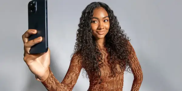 Mujer con cabello rizado oscuro toma selfie con iPhone. Muestra su estilo y los pasos del método curly.