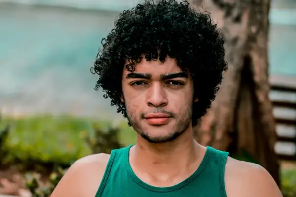 Hombre con cabello rizado y barba, luciendo un estilo natural que podría ser parte de un **método curly hombre**.