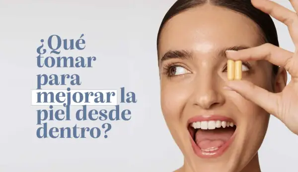Mujer sonriente sostiene dos cápsulas amarillas, preguntándose qué tomar para mejorar la piel de la cara desde dentro.