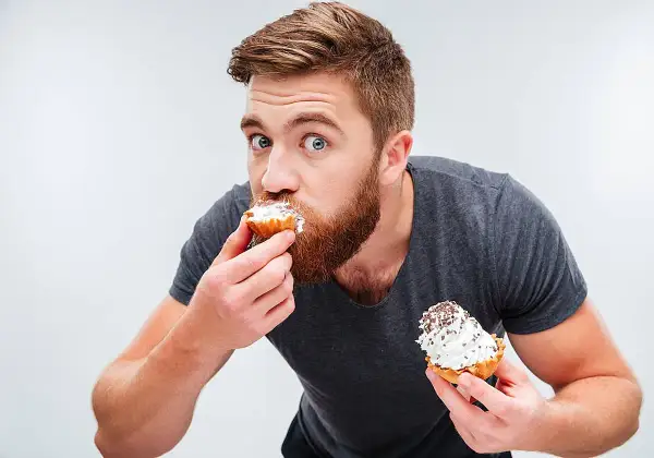 Hombre con barba comiendo pastelitos, ¿es esto un ejemplo de glicación?