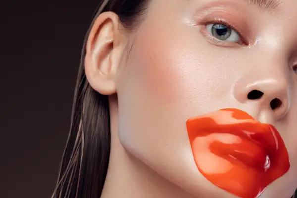 Labios rojos y brillantes cubren la boca de una mujer. Quizás para evitar que se diga que exfoliar los labios es malo.