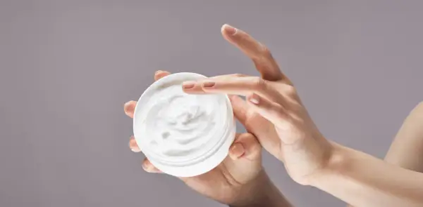 Manos aplicando crema hidratante. La urea en las cremas ayuda a retener la humedad, dejando la piel suave.