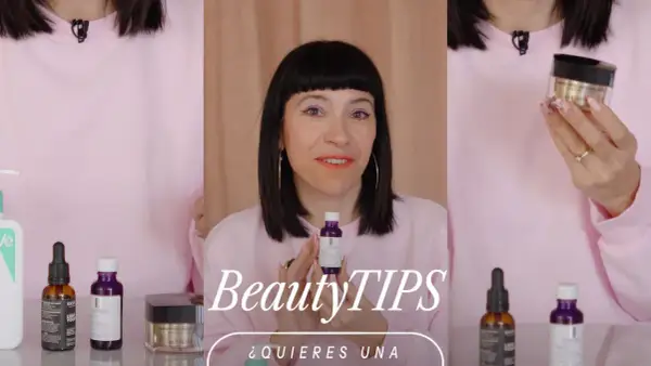 Mujer con maquillaje vibrante y un suéter rosa muestra productos de belleza, buscando un efecto glow cara.