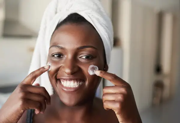 Sonrisa radiante con crema en mejillas, anticipando los resultados de retinol antes y después.